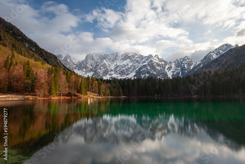 A beautiful green lake with reflections of snow-capped mountains.
