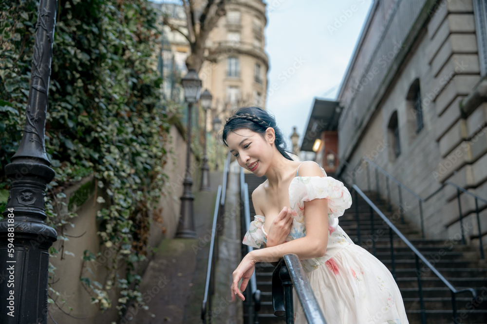 Woman in white dress walking on stairs in Paris, France.