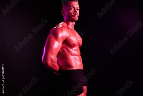 Fototapeta Naklejka Na Ścianę i Meble -  Man professional athlete with naked torso in sports uniform, isolated on multicolored background in neon light. Advertising, sports, active lifestyle, competition, challenge concept. 