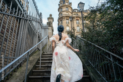 Woman in white dress walking on stairs in Paris, France.