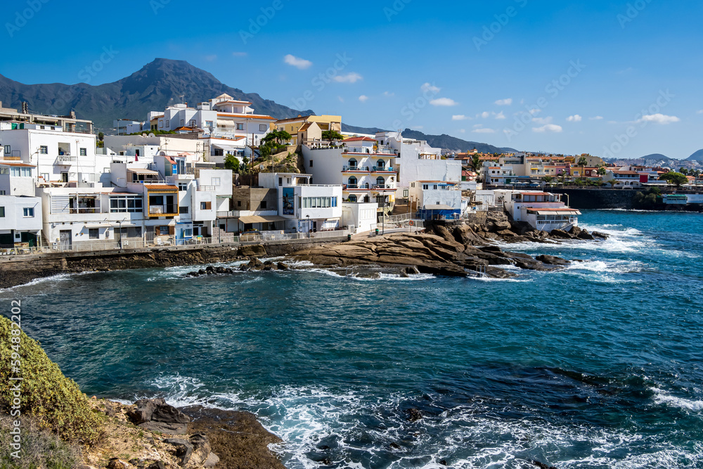 Tranquil retreat in the striking bay of La Caleta, Tenerife, featuring the idyllic Playa El Varadero beach, rocky coastline and picturesque village with Roque del Conde mountain peak in the background