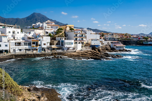 Tranquil retreat in the striking bay of La Caleta, Tenerife, featuring the idyllic Playa El Varadero beach, rocky coastline and picturesque village with Roque del Conde mountain peak in the background photo