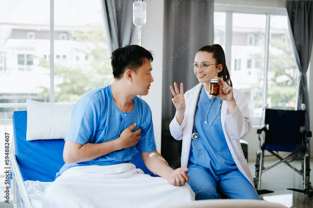 Doctor in white suit take notes while discussing and Asian elderly, man patient who lying on bed with receiving saline solution in hospital or clinic. Doctor in white suit take notes while discussing and Asian elderly, man patient who lying on bed with receiving saline solution in hospital or clinic.