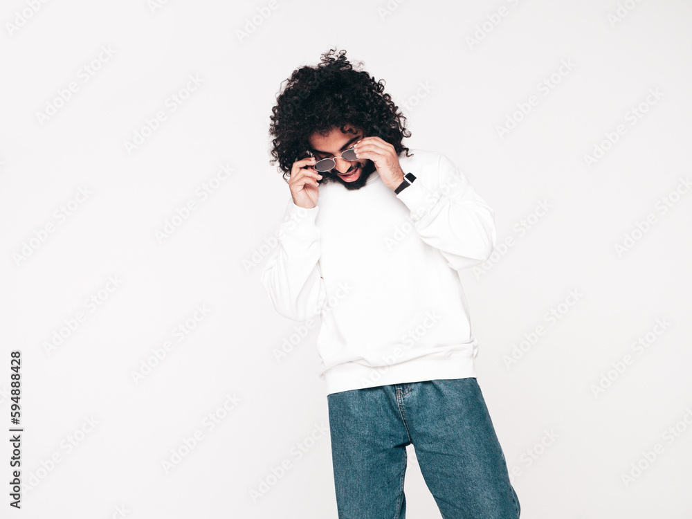 Handsome smiling hipster model. Unshaven Arabian man dressed in summer sweater and jeans clothes. Fashion male with long curly hairstyle isolated on white in studio. Copy space, mockup Handsome smiling hipster model. Unshaven Arabian man dressed in summer sweater and jeans clothes. Fashion male with long curly hairstyle isolated on white in studio. Copy space, mockup