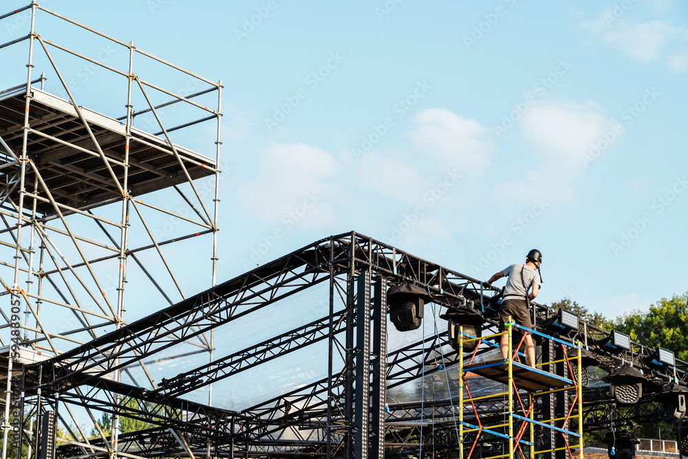 Installation of a street stage and lighting fixtures for public events and music concerts. unrecognizable person