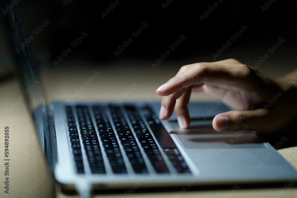 Close up of a man's hands on keyboard of lap top in the dark room, people working at home, modern white notebook. Internet, work, technology concept.