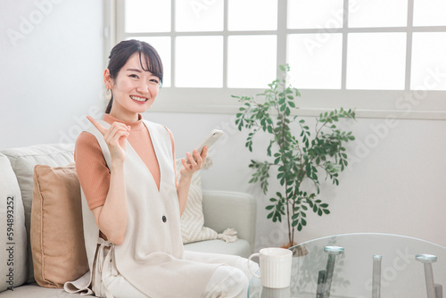 家でスマホを使う笑顔の日本人女性（アプリ・おすすめポーズ）
 photo