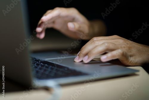 Close up of a man's hands on keyboard of lap top in the dark room, people working at home, modern white notebook. Internet, work, technology concept.