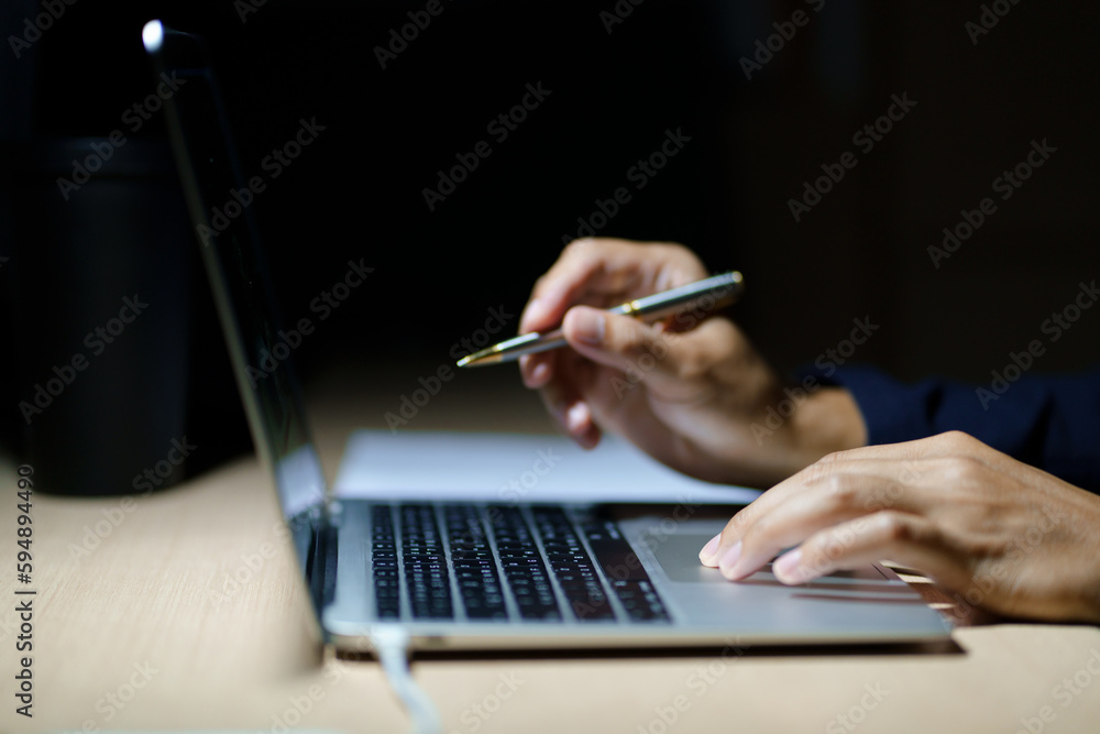 Business planning, E learning concept. Man hand with pen working on laptop computer at home office, close up, dark room. Student lecture while attending online course, information searching. Business planning, E learning concept. Man hand with pen working on laptop computer at home office, close up, dark room. Student lecture while attending online course, information searching.