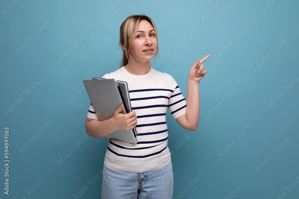 close-up of a successful blonde woman freelancer in a striped sweater holding a laptop in her hands on a blue background close-up of a successful blonde woman freelancer in a striped sweater holding a laptop in her hands on a blue background