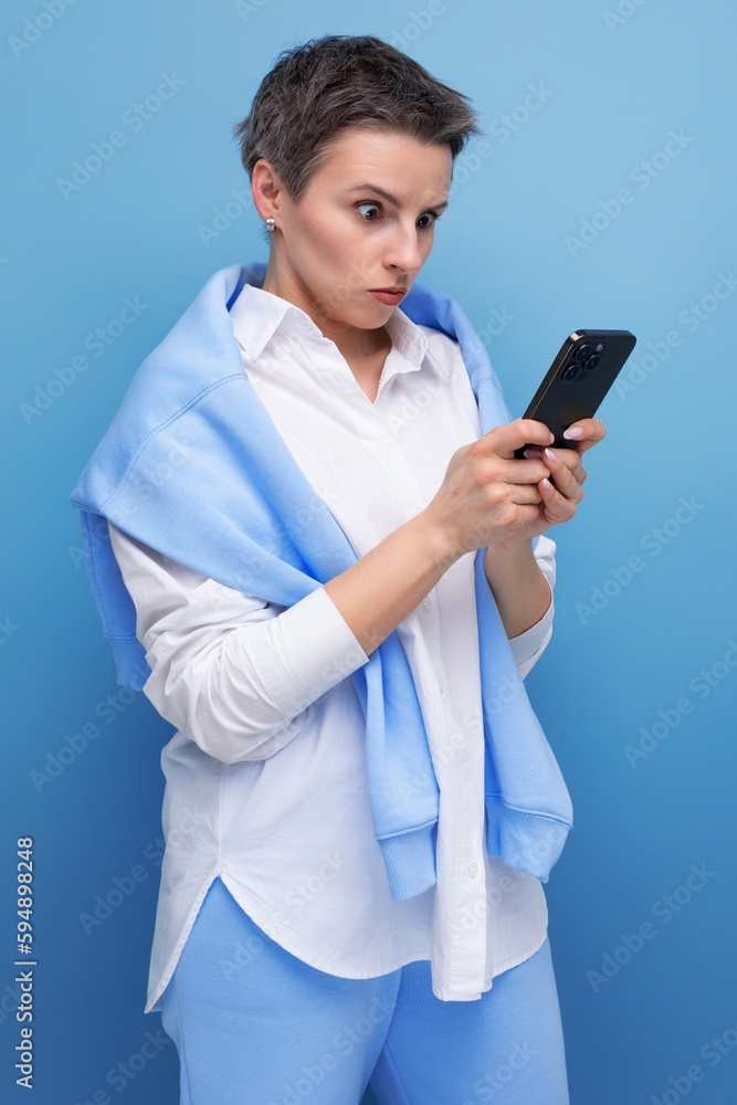concentrated young woman with short hair chatting online using smartphone concentrated young woman with short hair chatting online using smartphone