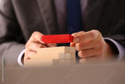 Businessman hand builds ladder from wooden blocks on top of red color. Achieving goals successful career and leadership concept