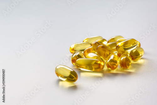 A close-up photo of several yellow capsules of fish oil on a white background. Copy space