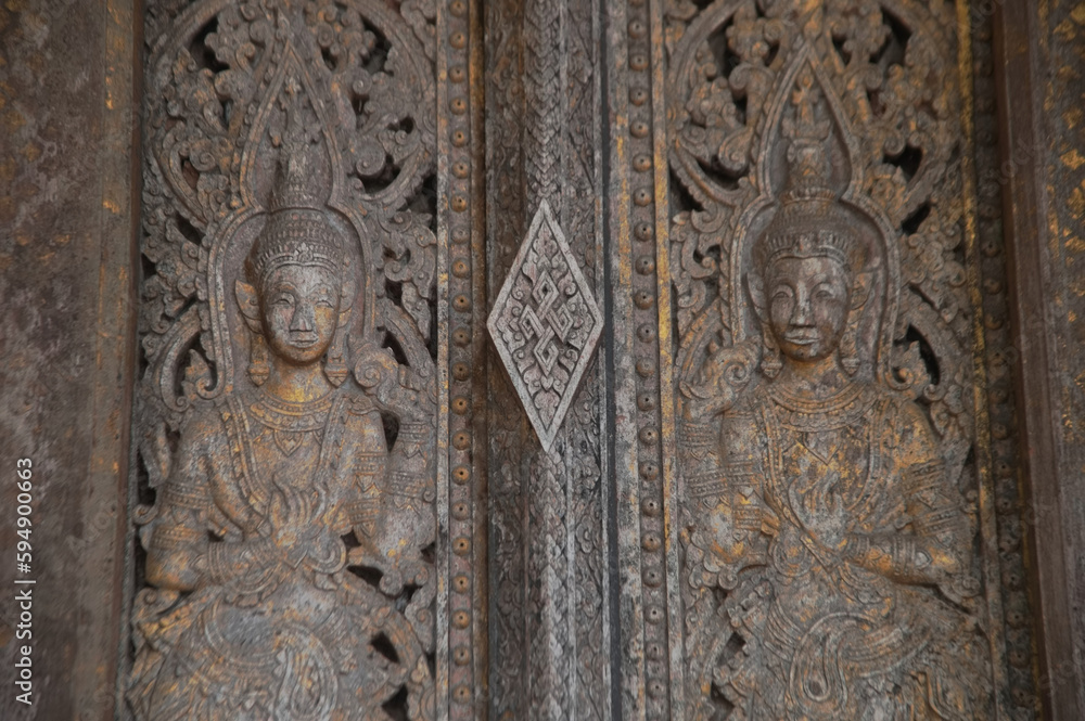 Patterns of angels carved from wooden on the church door of Wat Pa Ruak, which is an abandoned temple. Located at the way up Mount Phousi. At Central Luang Prabang city in Northern of Laos.
