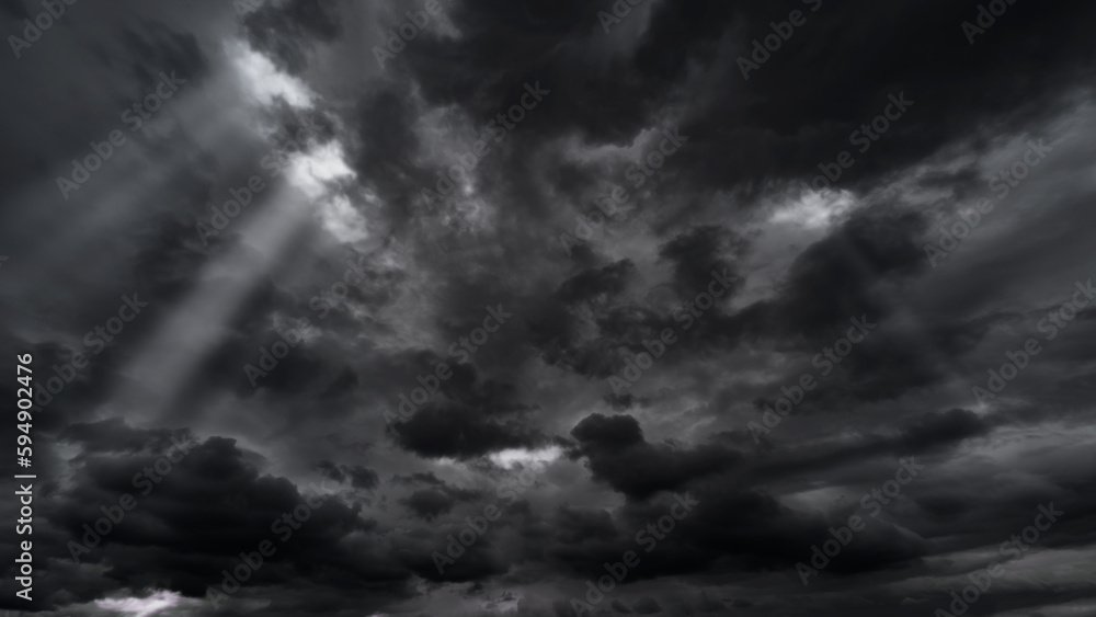 dark dramatic sky with black stormy clouds before rain or snow as abstract background, extreme weather, the sun shines through the clouds, high contrast photo