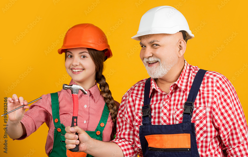 happy girl and grandfather carpenter in helmet on yellow background happy girl and grandfather carpenter in helmet on yellow background