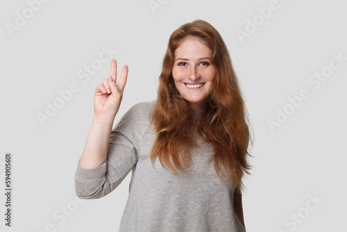 Cute friendly positive woman showing two finger on white background