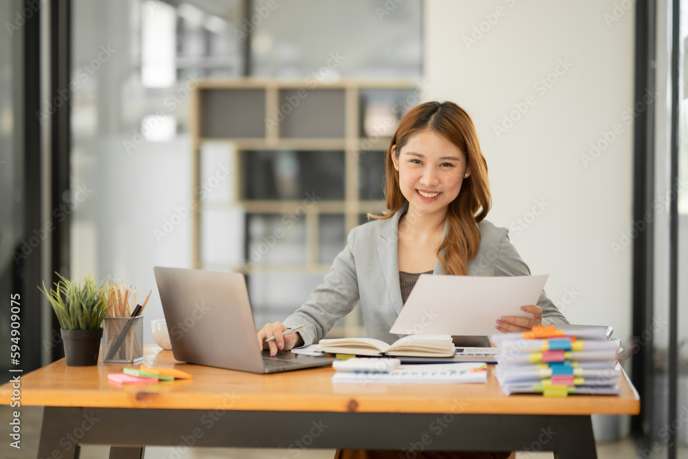 Asian businesswoman holding notebook about business, spending money Asian businesswoman holding notebook about business, spending money