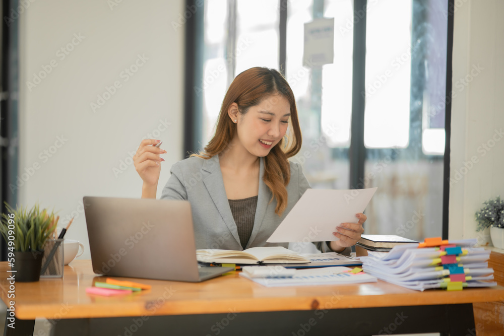 Asian businesswoman holding notebook about business, spending money Asian businesswoman holding notebook about business, spending money