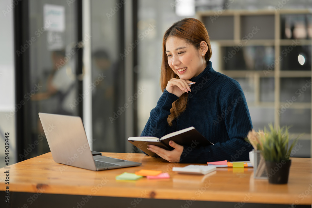 Fototapeta premium Asian businesswoman reading graphs and talking on phone with customers in office