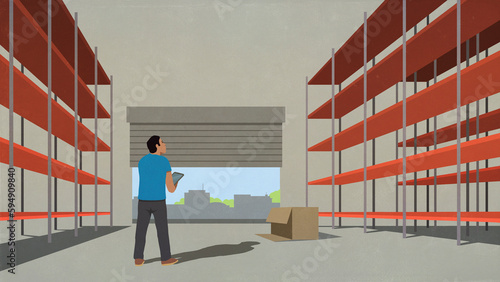 Man with digital tablet standing in empty distribution warehouse at loading dock
 photo