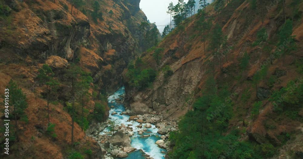 Drone shot of forest and river revealing lone figure in black jacket crossing suspension bridge at Nepal's Manaslu Circuit Trek. Breathtaking view beckon adventurers to explore the stunning landscape. Drone shot of forest and river revealing lone figure in black jacket crossing suspension bridge at Nepal's Manaslu Circuit Trek. Breathtaking view beckon adventurers to explore the stunning landscape.