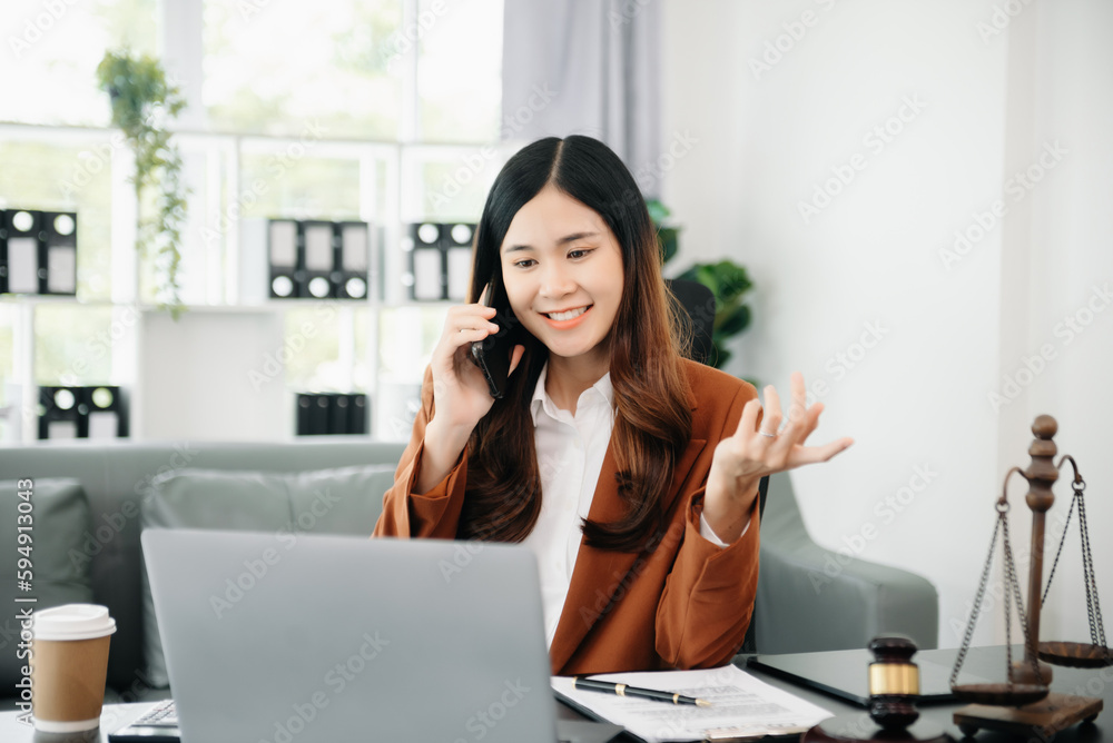 Obraz premium Asian female lawyer chatting online with client on laptop, smartphone discussing details of lawsuit. in office.