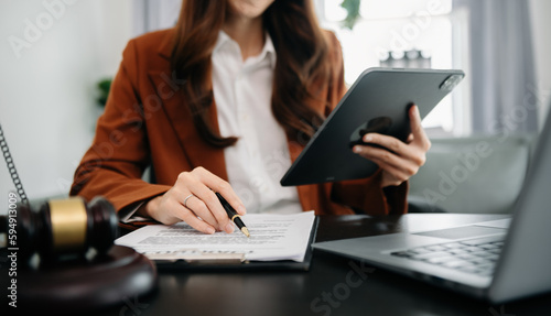 justice and law concept.Male judge in a courtroom  the gavel, working with smart phone and laptop and digital tablet computer on wood table in morning light .