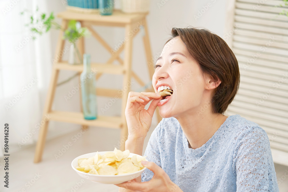 自宅で板ポテトチップスを食べる女性 自宅で板ポテトチップスを食べる女性