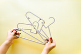 Hands holding baby hangers on yellow background