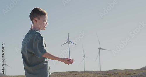 Happy child on looking at wind energy turbine sat wind farm site, alternative energy, wind farm and happy time with your family, Earth Day	