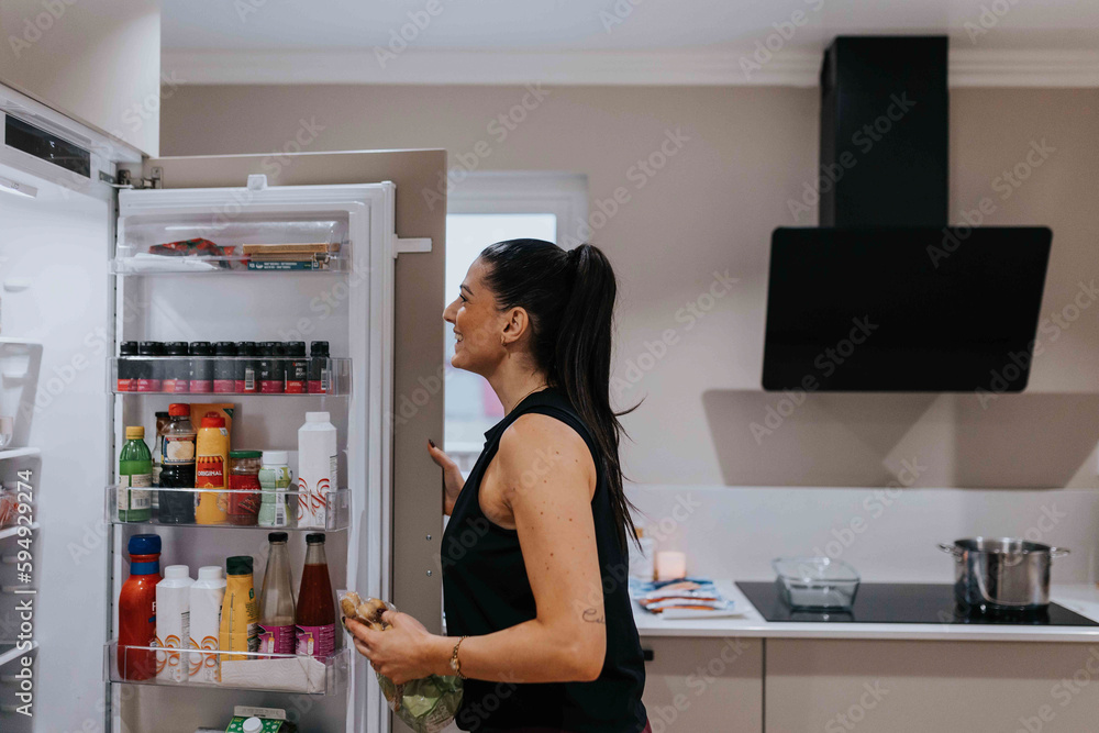 Woman standing in front of open fridge Woman standing in front of open fridge