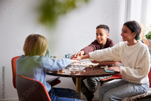 Girl and boys playing scrabble at dining table photo