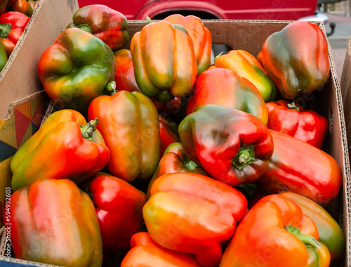 Obraz na płótnie Red, green and yellow bell peppers in cardboard boxes on the counter. Close-up. Selling bell peppers at the vegetable market. w salonie