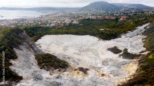 Aerial view of Solfatara of Pozzuoli, near Naples, Italy. It is a dormant volcano and part of the Phlegraean Fields volcanic area. In background there are Pozzuoli town and Mediterranean sea. photo
