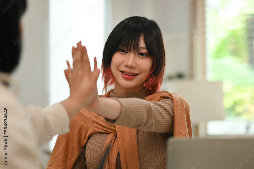 Pretty young creative woman celebrating success and giving high five with colleagues. Good teamwork, corporate success, victory Pretty young creative woman celebrating success and giving high five with colleagues. Good teamwork, corporate success, victory