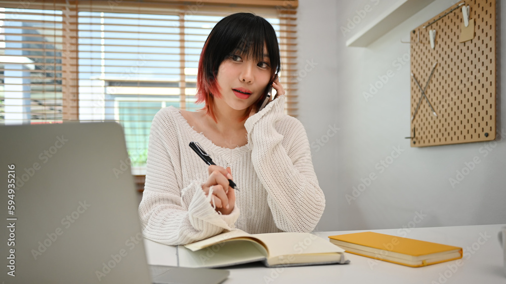 Young start up small business owner taking order from customer, talking on mobile phone at workplace Young start up small business owner taking order from customer, talking on mobile phone at workplace