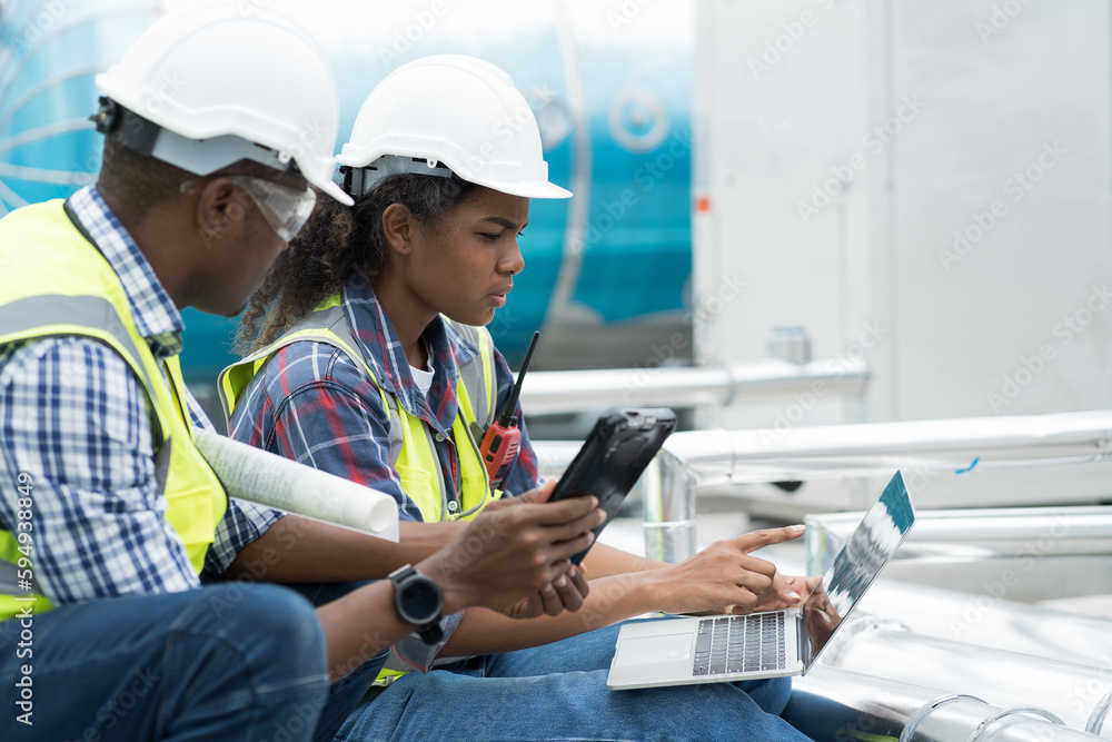 Male and female engineer worker working with laptop computer discuss and inspecting structure of building at rooftop of building at construction site Male and female engineer worker working with laptop computer discuss and inspecting structure of building at rooftop of building at construction site