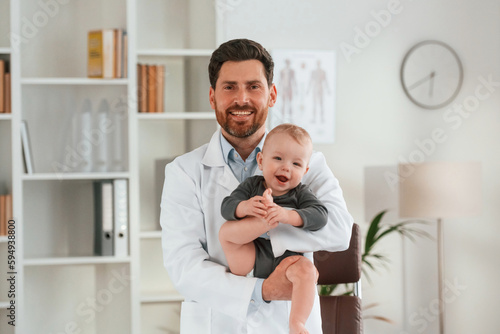 Standing and holding boy. Doctor with little baby is working in the cabinet © standret