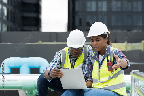 Male and female engineer worker working with laptop computer discuss and inspecting structure of building at rooftop of building at construction site © amorn