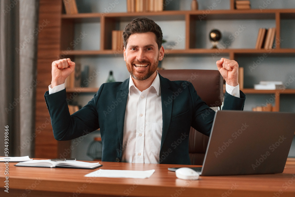 Celebrating success. Businessman in formal clothes is working indoors Celebrating success. Businessman in formal clothes is working indoors