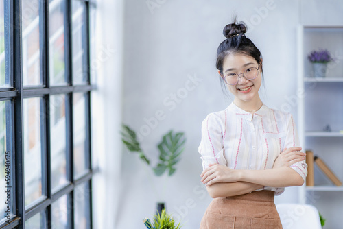 Smiling young beautiful Asian young woman, beautiful, confident and attractive in green sweater and eyeglasses in classroom or office. she was smiling happily