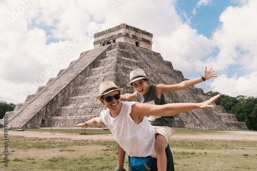 Mother and daughter happily opening their arms near the pyramid in Chichen Itza. Yucatan, Mexico photo