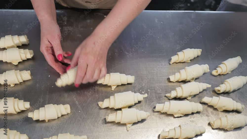 The baker forms croissants from the dough. Confectionery made from dough. Twisting the dough for Croissant production The baker forms croissants from the dough. Confectionery made from dough. Twisting the dough for Croissant production