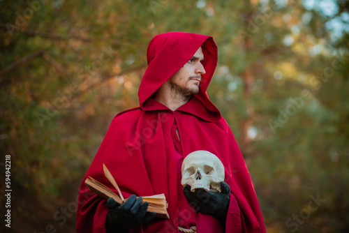 A sorcerer in red clothes with a skull and a book in his hands reads a spell. Medieval monk reads a prayer.