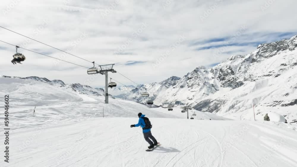 Follow shot of couple snowboard and ski downhill on a slope in Cervinia ski resort with mountain view Follow shot of couple snowboard and ski downhill on a slope in Cervinia ski resort with mountain view