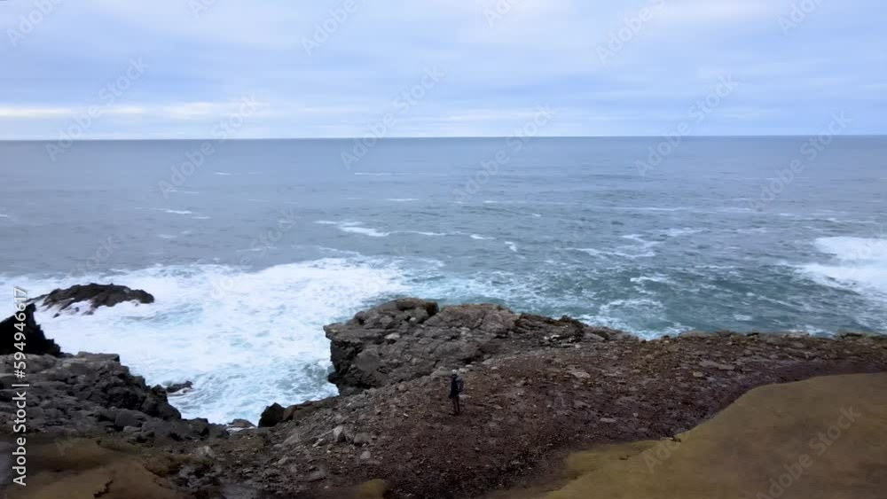 Man on Cliff watch Stac a' Phris Arch, Isle of Lewis, Scotland, Aerial Shot