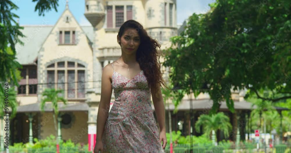 Latina walks in a park with hair flowing in the wind and a castle in the background Latina walks in a park with hair flowing in the wind and a castle in the background