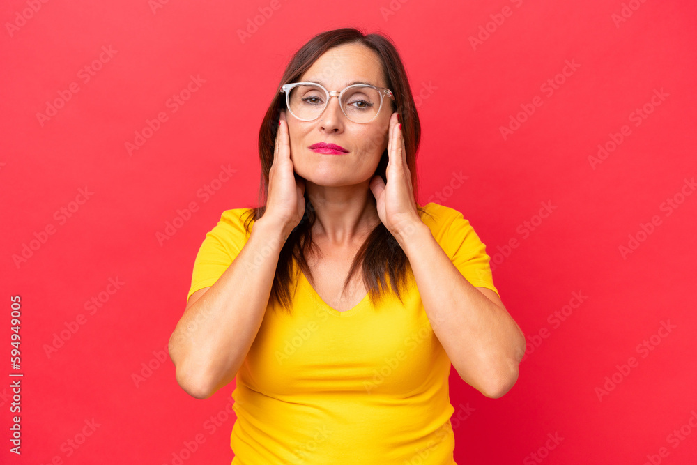 Middle-aged caucasian woman isolated on red background frustrated and covering ears Middle-aged caucasian woman isolated on red background frustrated and covering ears