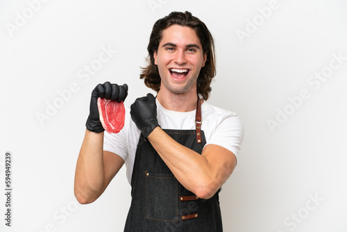 Butcher handsome man wearing an apron and serving fresh cut meat isolated on white background celebrating a victory